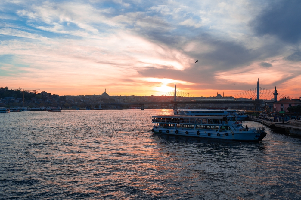 Bosphorus cruise boat at sunset with Istanbul skyline in the background